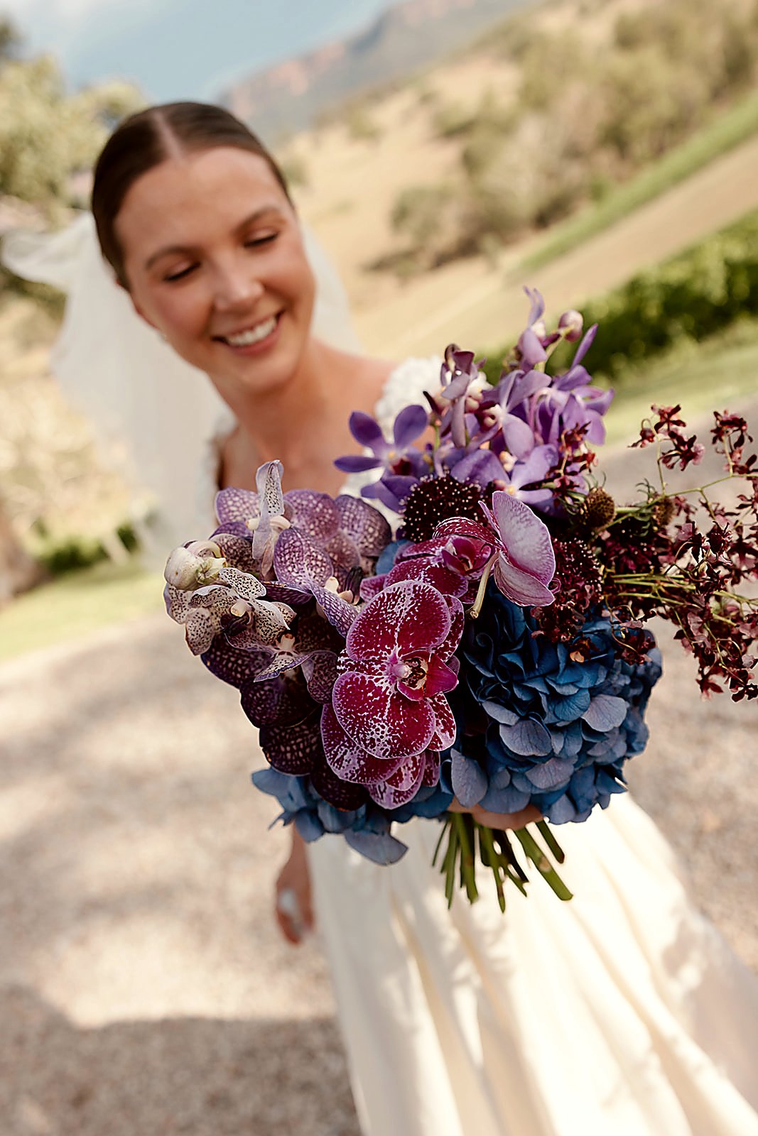 Bride holding a vivid purple and blue vanda orchid bouquet