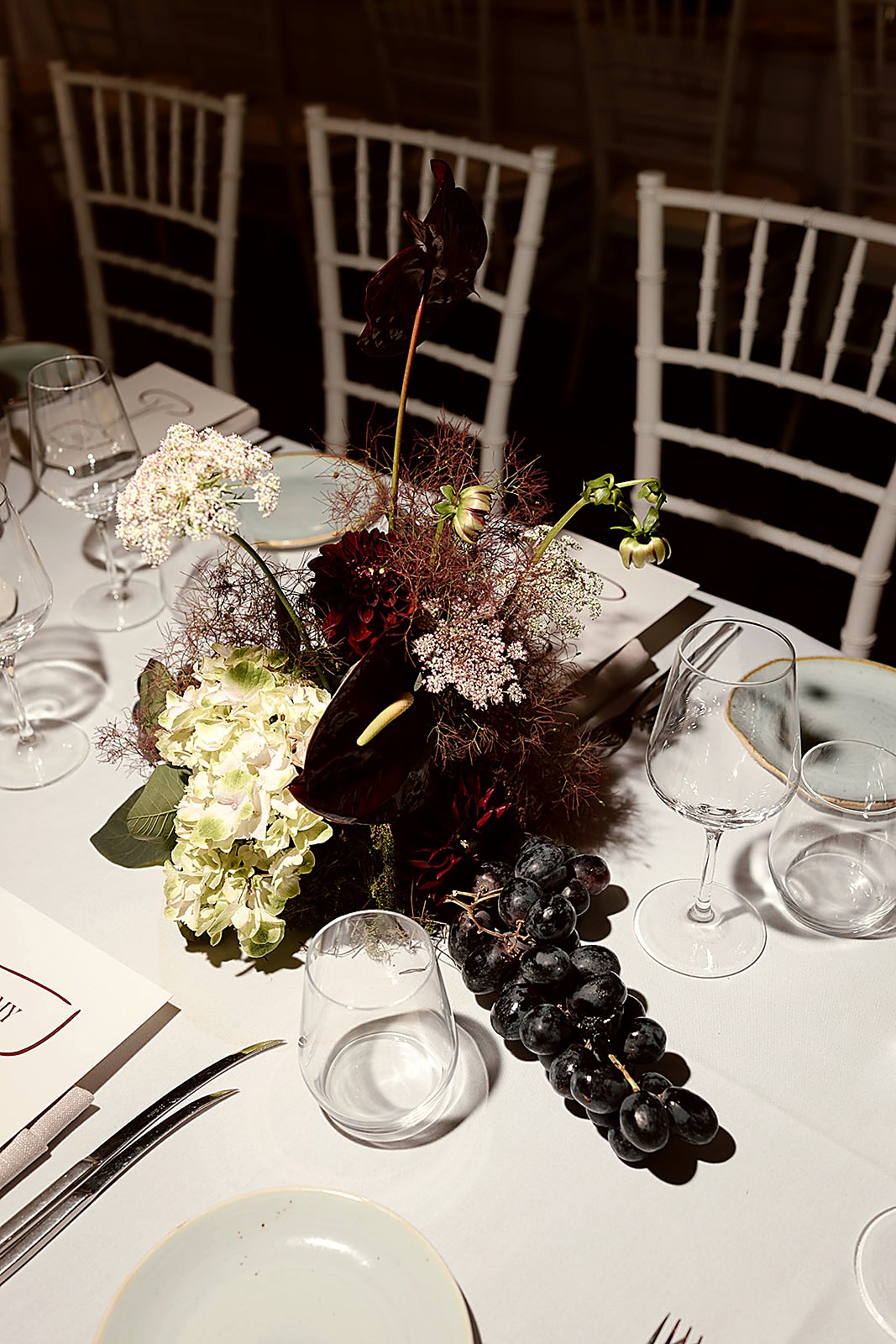 Moody event floral arrangement with grapes and dark anthurium